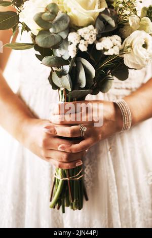 Il bouquet perfetto è sempre perfetto per il vostro abito da sposa. Una sposa irriconoscibile che tiene un bouquet di fiori il giorno del suo matrimonio. Foto Stock