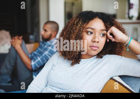 Coppia infelice e donna triste sconvolta dopo argomento o conflitto con il suo uomo sul divano di casa. Ragazza arrabbiata o femmina che pensa al disaccordo o. Foto Stock