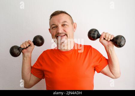 Vecchi e divertenti manubri di sollevamento maschile che si allenano in una casa Foto Stock
