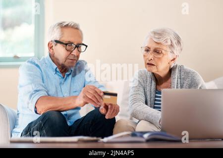 Non tutte le transazioni hanno bisogno di un viaggio alla banca. Una coppia anziana che usa una carta di credito mentre passa attraverso il lavoro di ufficio nel paese. Foto Stock