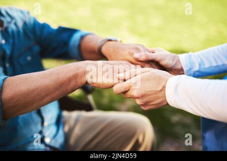 Im qui per portare la felicità. Una donna irriconoscibile che tiene le mani di un uomo anziano. Foto Stock