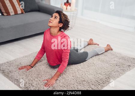 La mia schiena mi sembra incredibile quando faccio questa posa. Scatto a tutta lunghezza di una giovane donna attraente che fa yoga nella sua vita e tenendo un cane rivolto verso l'alto Foto Stock