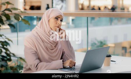 Pensieroso pensivo preoccupato giovane scrittore arabo che lavora su laptop pensa che nuova idea startup sviluppa piano scrive novel trova soluzione al problema Foto Stock