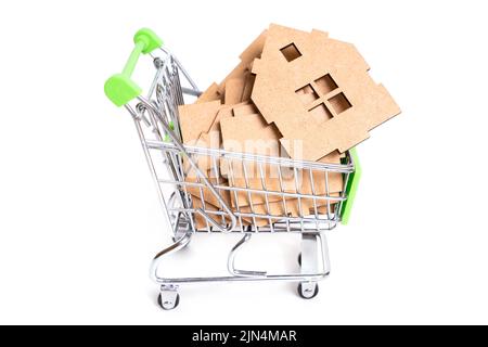 Parti di una casa in legno in miniatura in un piccolo carrello a spinta isolato su bianco. Concetto di costruzione prefabbricata. Foto Stock