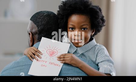 Primo piano carino sorridente ragazzo ragazza abbraccio papà congratularsi per la vacanza prendersi cura di figlia dà a mano scheda di amato papà carino adorabile bambini desideri Foto Stock