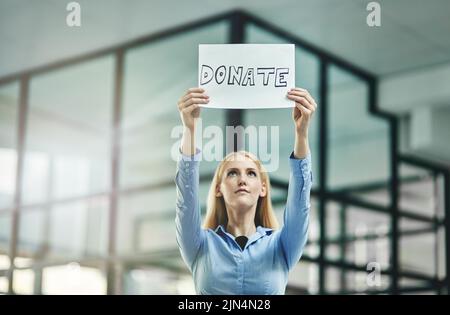 Donazione, beneficenza e raccolta fondi tenendo un cartello e chiedendo aiuto e supporto in sede aziendale. Donna d'affari e fondazione caritativa Foto Stock