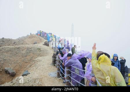 YANBIAN, CINA - 7 AGOSTO 2022 - i turisti visualizzano il Lago Tianchi alla vetta protetta dalla nebbia sulla pendenza settentrionale del monte Changbai nel nord-est della Cina Foto Stock