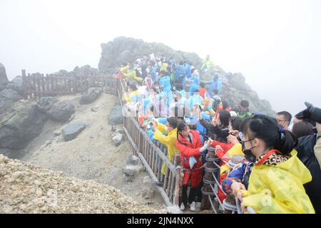 YANBIAN, CINA - 7 AGOSTO 2022 - i turisti visualizzano il Lago Tianchi alla vetta protetta dalla nebbia sulla pendenza settentrionale del monte Changbai nel nord-est della Cina Foto Stock