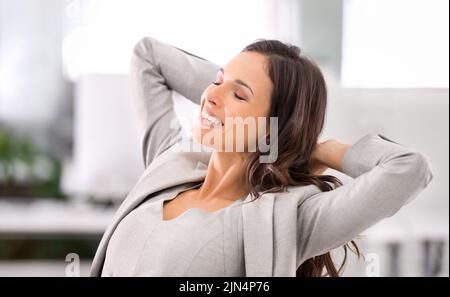 Felice, calma e rilassata donna d'affari sorridente sensazione di stress libero. Donna seduta in sedia con le mani dietro la testa. Donna soddisfatta seduta e. Foto Stock