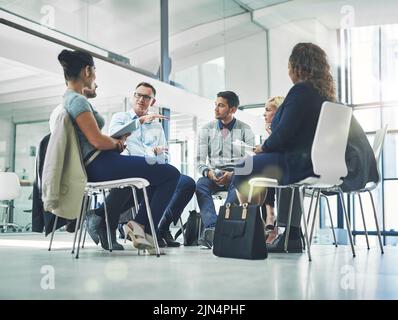 Gruppo di professionisti che parlano insieme in un cerchio per una riunione di squadra. Un gruppo di dipendenti di design e leader senior che lavorano, avendo Foto Stock