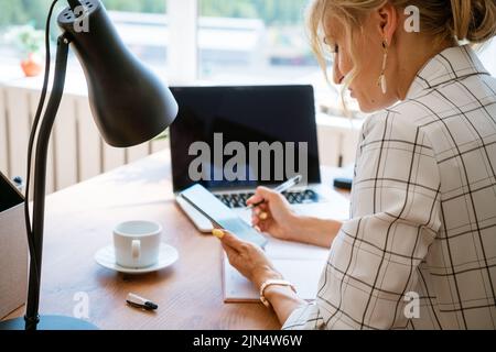 Processo di lavoro concettuale in ufficio. Giovane donna che lavora al progetto universitario con un notebook di design generale. L'analisi progetta le mani, in un vestito di affari Foto Stock
