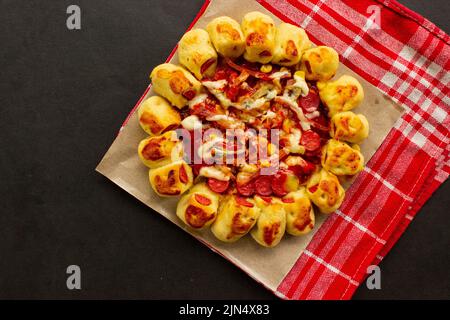 deliziosa pizza servita con condimento di funghi, mais, salsiccia di pollo, pancetta, maionese, salsa barbecue, pomodoro, peperoncino su sfondo nero. Foto Stock