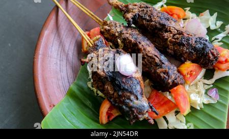 il bontel di sate o il bontel di satay è fatto di montone tritato avvolto in grasso di montone e poi cotto alla griglia. condimento con pomodori, scalogni, pepe, cavbag Foto Stock