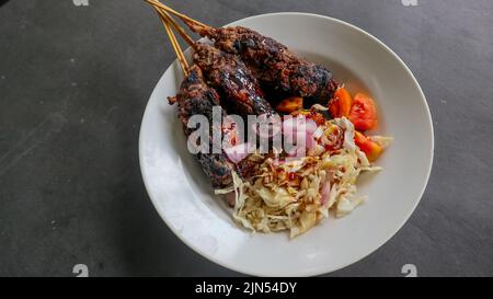 il bontel di sate o il bontel di satay è fatto di montone tritato avvolto in grasso di montone e poi cotto alla griglia. condimento con pomodori, scalogni, pepe, cavbag Foto Stock