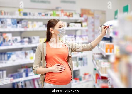 donna incinta in maschera acquista medicina in farmacia Foto Stock