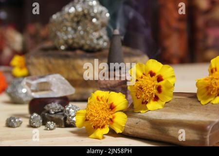 Cono di incenso su pietra con cristalli e fiori Foto Stock