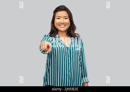 donna asiatica felice che punta il dito alla macchina fotografica Foto Stock