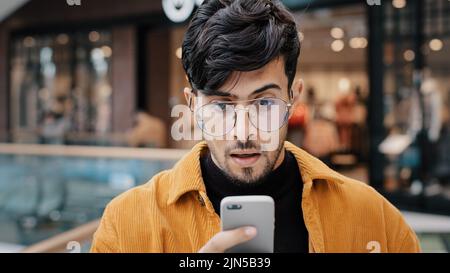 Giovane ragazzo che guarda lo schermo dello smartphone leggere e-mail con grandi notizie sorpreso gioire celebrare successo vincere gioco d'azzardo online ha ottenuto Foto Stock