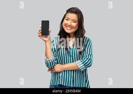 Felice donna asiatica su sfondo grigio Foto Stock