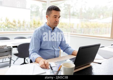 uomo in cuffie con computer portatile che lavora a casa Foto Stock