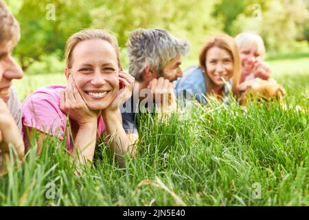 Felice giovane donna che si rilassa con gli amici in erba su un prato estivo Foto Stock
