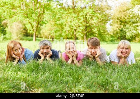 La famiglia o gli amici si prendono una pausa in un prato in estate e si trovano rilassati in erba Foto Stock