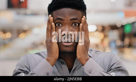 Primo piano ritratto maschile giovane sorpreso stupito eccitato scioccato grave afroamericano che tiene le mani sulla faccia sorpresa dicendo wow ottenere Foto Stock