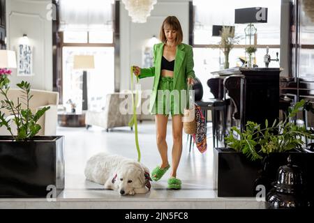 Donna d'affari con cane nella hall dell'hotel di lusso Foto Stock