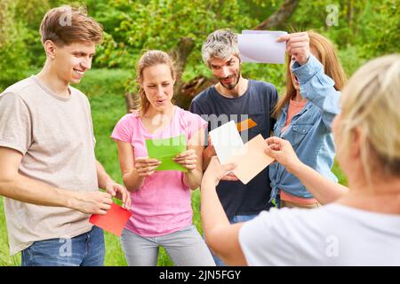 Gruppo di giovani che giocano a team building con carte colorate per l'integrazione e lo spirito di squadra Foto Stock