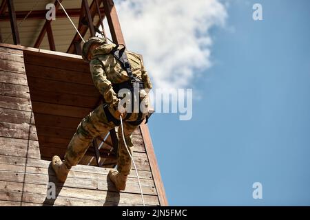 Militare climbing net durante il percorso ad ostacoli in boot camp Foto Stock