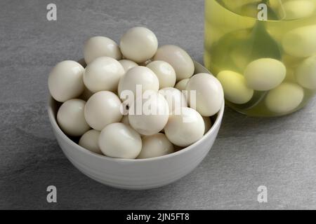 Ciotola con le uova intere cotte conservate vicino e un vaso di vetro sullo sfondo Foto Stock