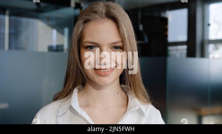 Primo piano ritratto caucasico felice soddisfatto sicuro studente femmina sorridente toothy sorriso riuscito modello di donna bella posa in casa guardando Foto Stock