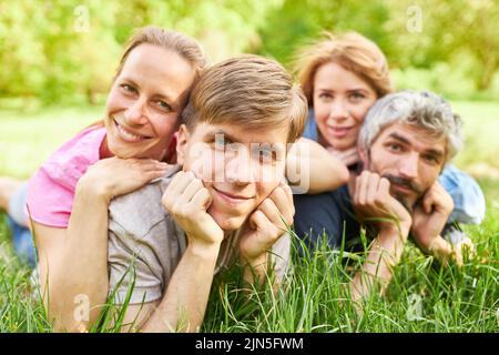 Due giovani coppie felici si trovano in erba su un prato in estate e rilassarsi Foto Stock