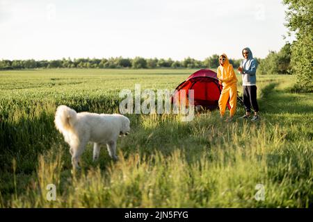 Le giovani coppie giocano con il loro cane al campeggio Foto Stock