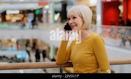 Matura donna felice parla amichevole al telefono risponde chiamata comunica con la famiglia utilizzando smartphone gioiosa di mezza età colloqui a distanza gossiping su Foto Stock