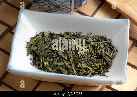 Ciotola con Sencha superiore tè verde secco lascia da vicino Foto Stock