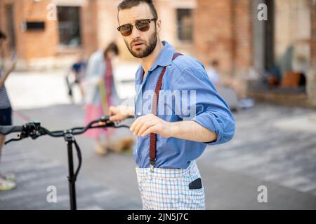 Ritratto di un ragazzo elegante con scooter elettrico all'aperto Foto Stock