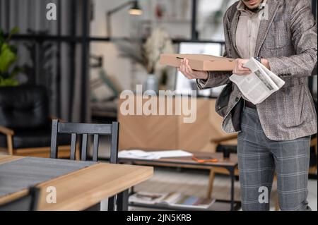 Uomo che tiene la scatola del giornale che guarda l'orologio Foto Stock