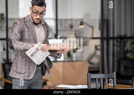 Uomo con scatola che guarda il orologio da polso in sorpresa Foto Stock