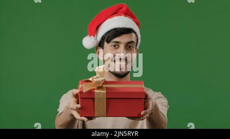 L'uomo arabo in cappello rosso di Santa tiene il regalo grande scatola rossa con nastro d'oro desidera nuovo anno celebrazione di Natale amichevole indiano che mostra presente Foto Stock