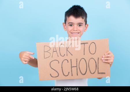 un bambino sorridente tiene in mano un segno di ritorno a scuola Foto Stock