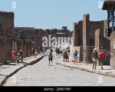 Strada nel sito di scavi di Pompei con molti turisti che visitano la città romana. Pompei, Campania, Italia Foto Stock