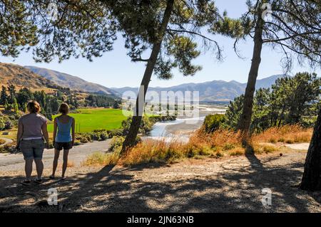 Due giovani visitatori che ammirano il fiume Waiau vicino al resort Hanmer Hot Springs & Spa nelle pianure di Canterbury sull'Isola del Sud in Nuova Zelanda Foto Stock