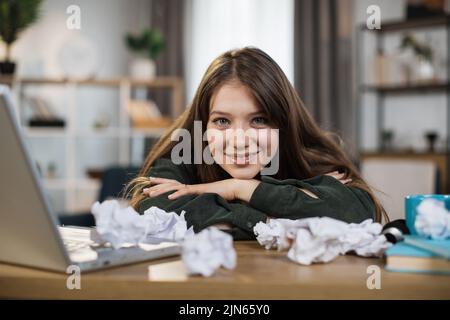 Immagine interna di donna sorridente e stanca che dorme sul tavolo. Giovane donna adulta di lavoro fatica dormire sul tavolo in ufficio. Donna d'affari stanca del lavoro straordinario. Foto Stock