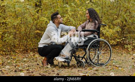 Giovane felice ispanico coppia in amore avere conversazione cute parlare ragazzo cure visite ragazza malato in ospedale parco donna paziente in Foto Stock