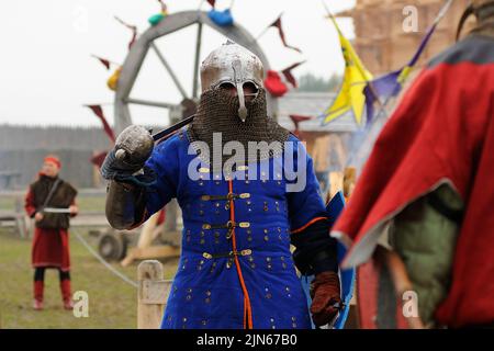 Uomo del Reenattore vestito in armatura di un vecchio Rus footman ricostruire la lotta di spada, fortezza di legno su uno sfondo. Kiev, Ucraina Foto Stock