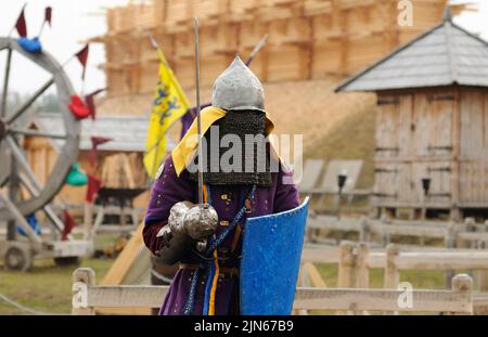 Uomo del Reenattore vestito in armatura di un vecchio Rus footman ricostruire la lotta di spada, fortezza di legno su uno sfondo. Kiev, Ucraina Foto Stock