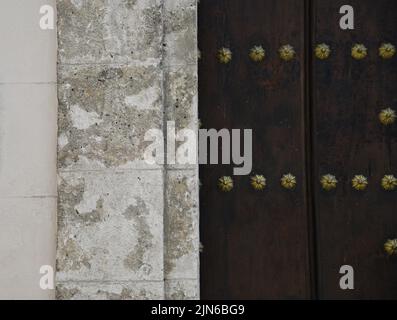 Antica porta in legno massello di quercia con borchie in bronzo contro un antico muro di pietra nella Vecchia Avana, Cuba. Foto Stock