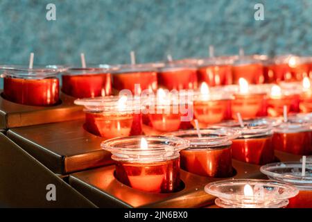 Un primo piano di candele rosse in vasetti di vetro nei supporti Foto Stock
