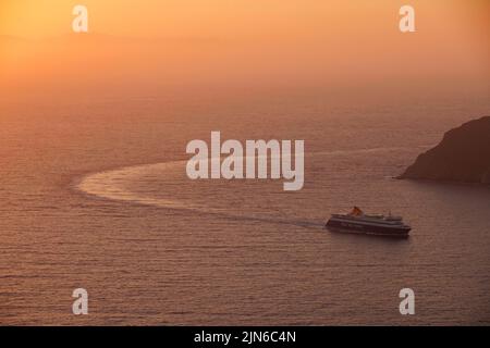 Il traghetto Blue Star Naxos arriva al porto di Aiyiali ad Amorgos in Grecia al tramonto. Foto Stock